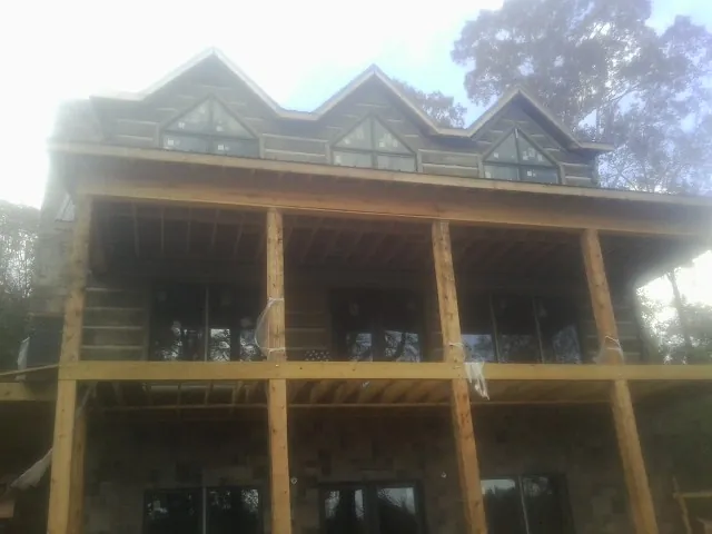 Dormers and porch framing on a large log home under construction — Roof Coating work by our crew in Waynesville