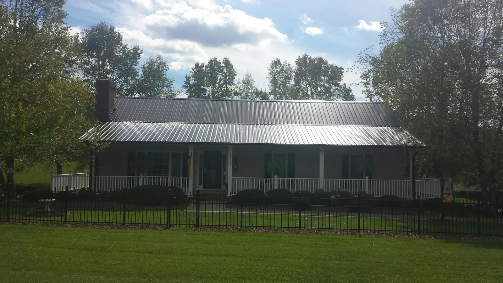 Gray metal roof on a brick ranch with a full width front porch — Gutter Guard Installation work by our crew in Waynesville