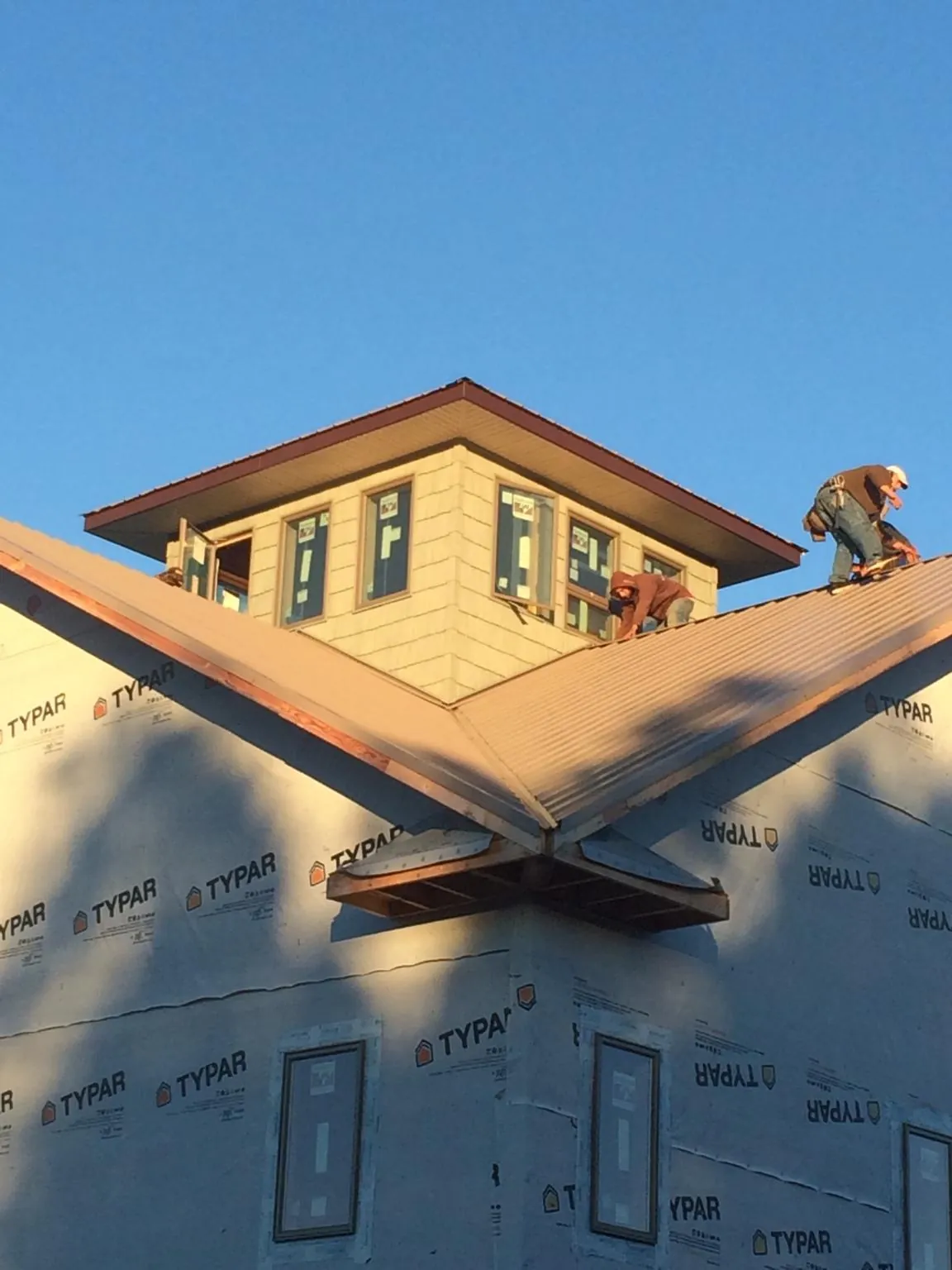 Roofers working around a rooftop cupola on a new metal roof at sunset — Roof Waterproofing in Waynesville by Roofing Brothers